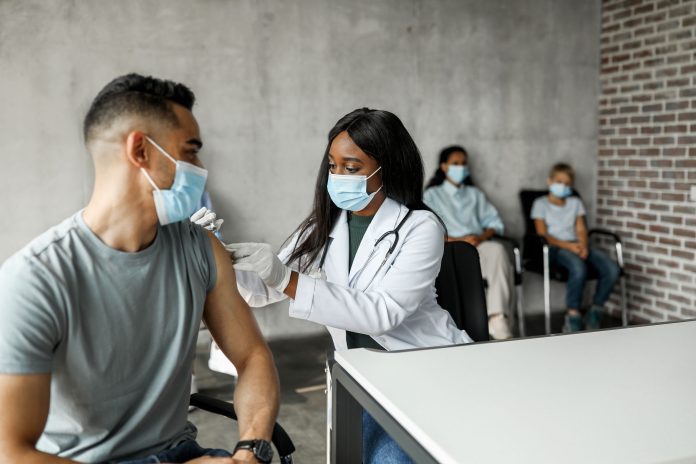 Arabic man getting intramuscular shot against COVID-19 at clinic